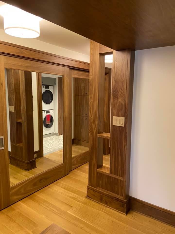 Wood-paneled hallway with mirrored closet doors and a small alcove under a low wooden ceiling