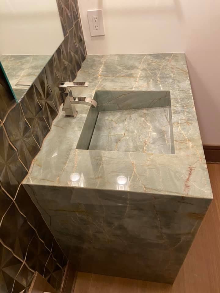 Bathroom vanity with gray stone countertop, square sink, and chrome faucet beside a wall mirror