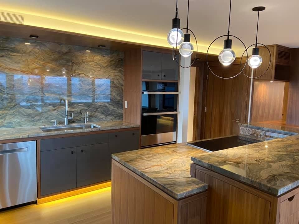 Modern kitchen with wood cabinets, granite island, pendant lights, and a large window backsplash