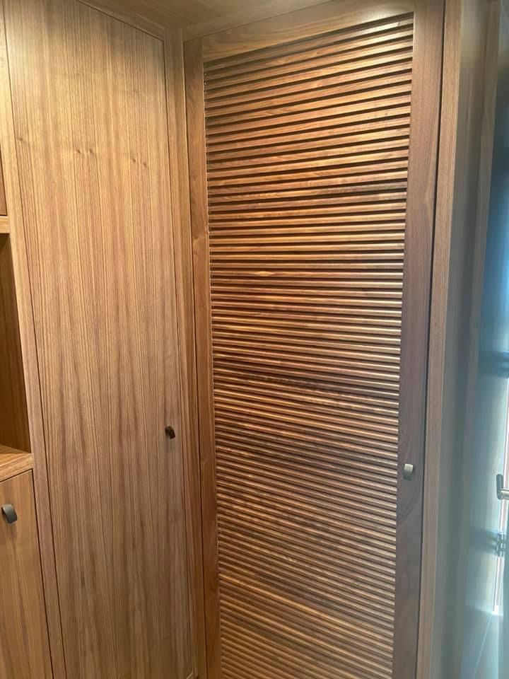 Wood-paneled hallway with a slatted wooden closet door and a glass door on the right.