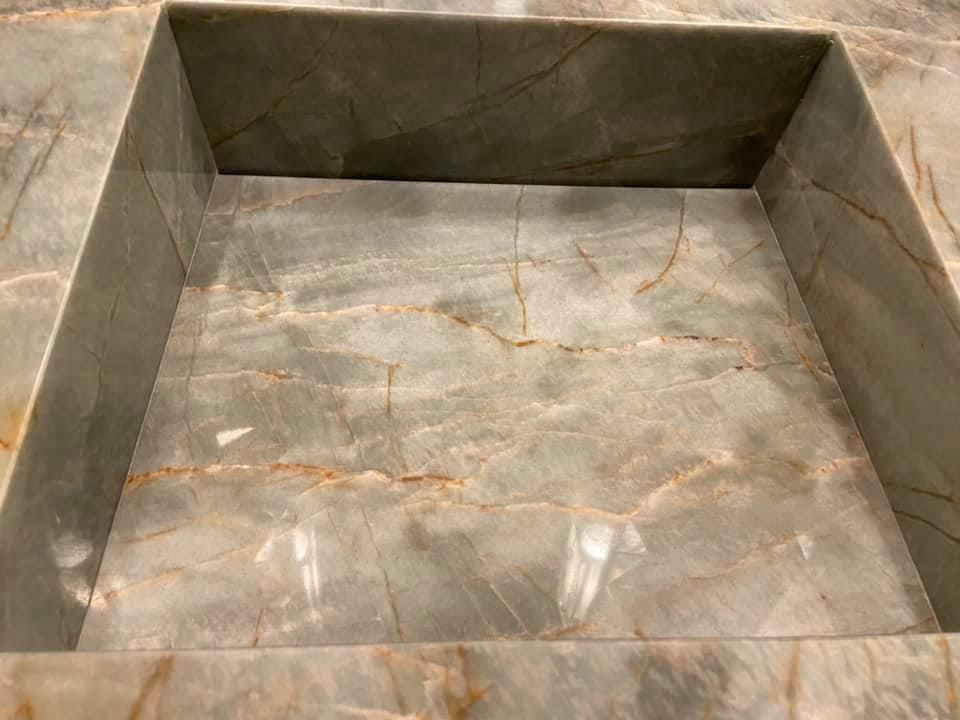 Empty gray stone or marble box with raised sides and a worn, marbled interior surface