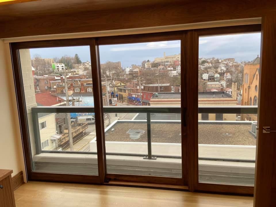 Wood-framed window overlooking a cityscape with balconies and rooftops