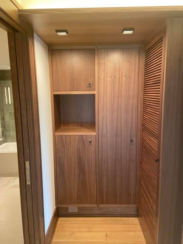 Wood-paneled hallway alcove with built-in shelves, cabinets, and louvered doors.