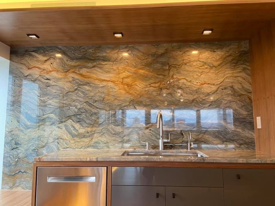 Modern kitchen with wood cabinets and a stone backsplash behind a sink and faucet