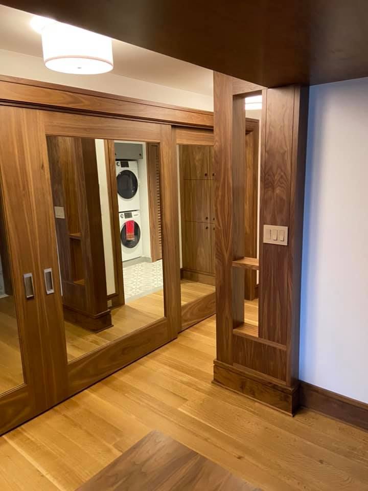 Wood-paneled hallway with mirrored closet doors, wood floor, and a hanging ceiling light.