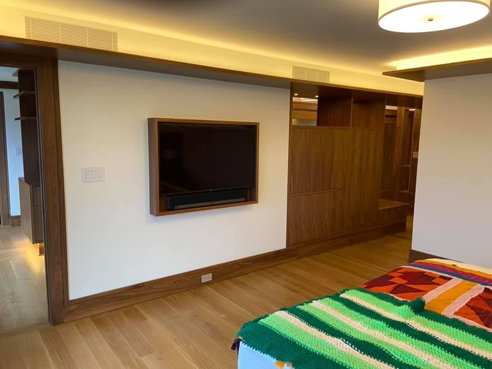 Modern bedroom with wall-mounted TV, wood flooring, and colorful striped bedding