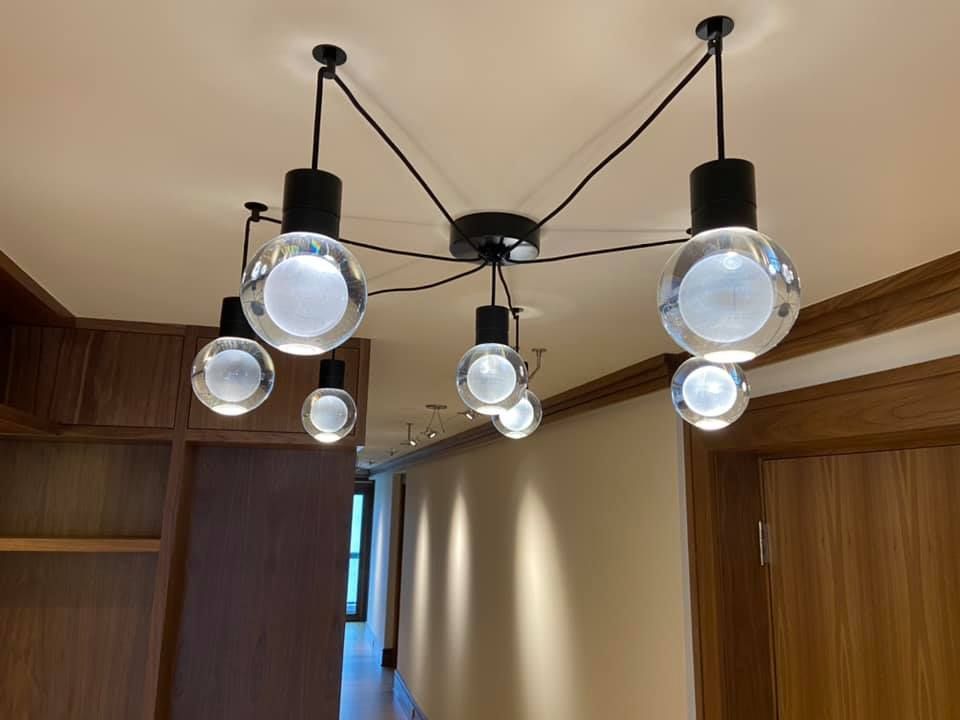 Ceiling light fixture with five hanging bulbs in a wood-paneled hallway