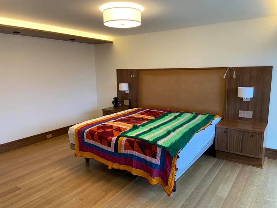 Modern bedroom with a colorful patterned bedspread, wooden headboard, and bedside tables