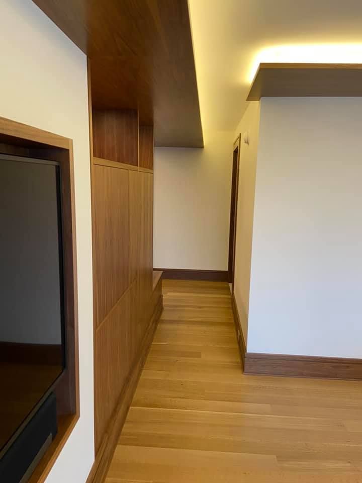 Narrow hallway with wood flooring, built-in cabinets, and warm ceiling lights.