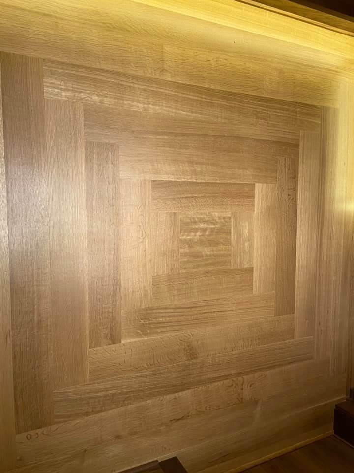 Wooden wall panel with a layered square geometric design in warm light tones