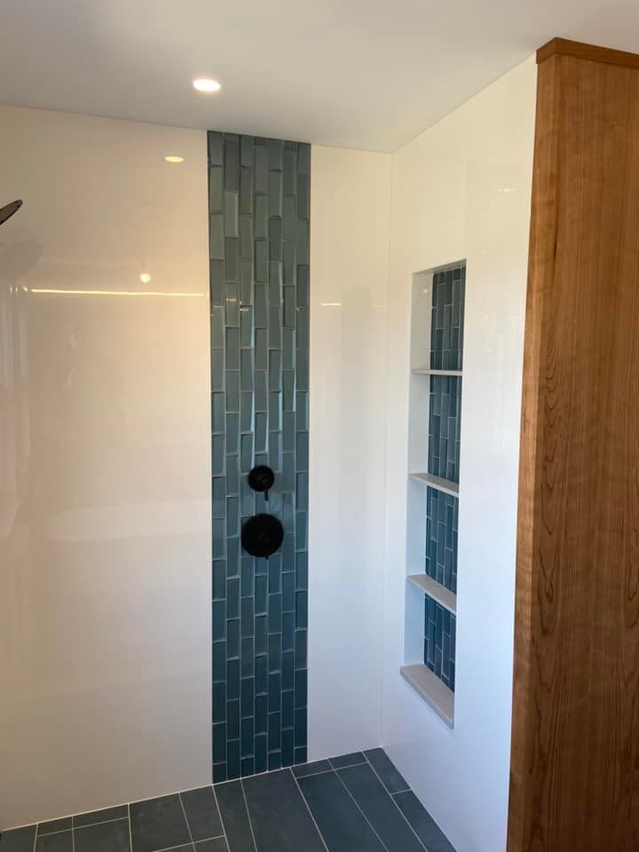 Modern bathroom shower with blue tile accent wall, white walls, and built-in recessed shelf.