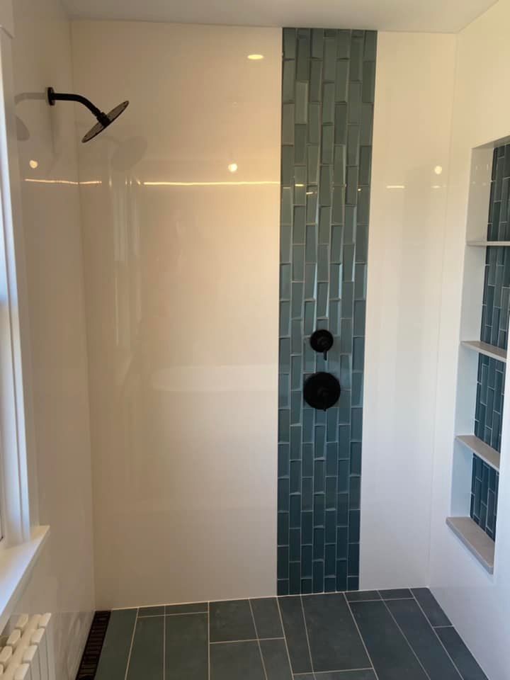 Empty shower with white walls, teal tile accent strip, black fixtures, and frosted glass shelves.