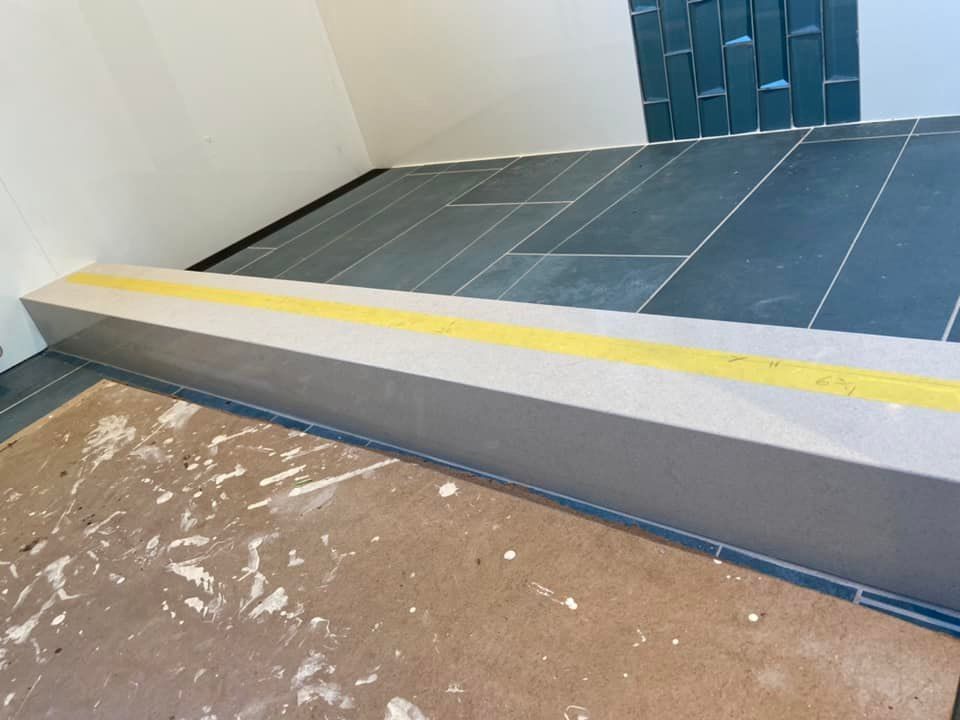 Indoor ramp with a yellow safety strip beside blue-gray tiled flooring