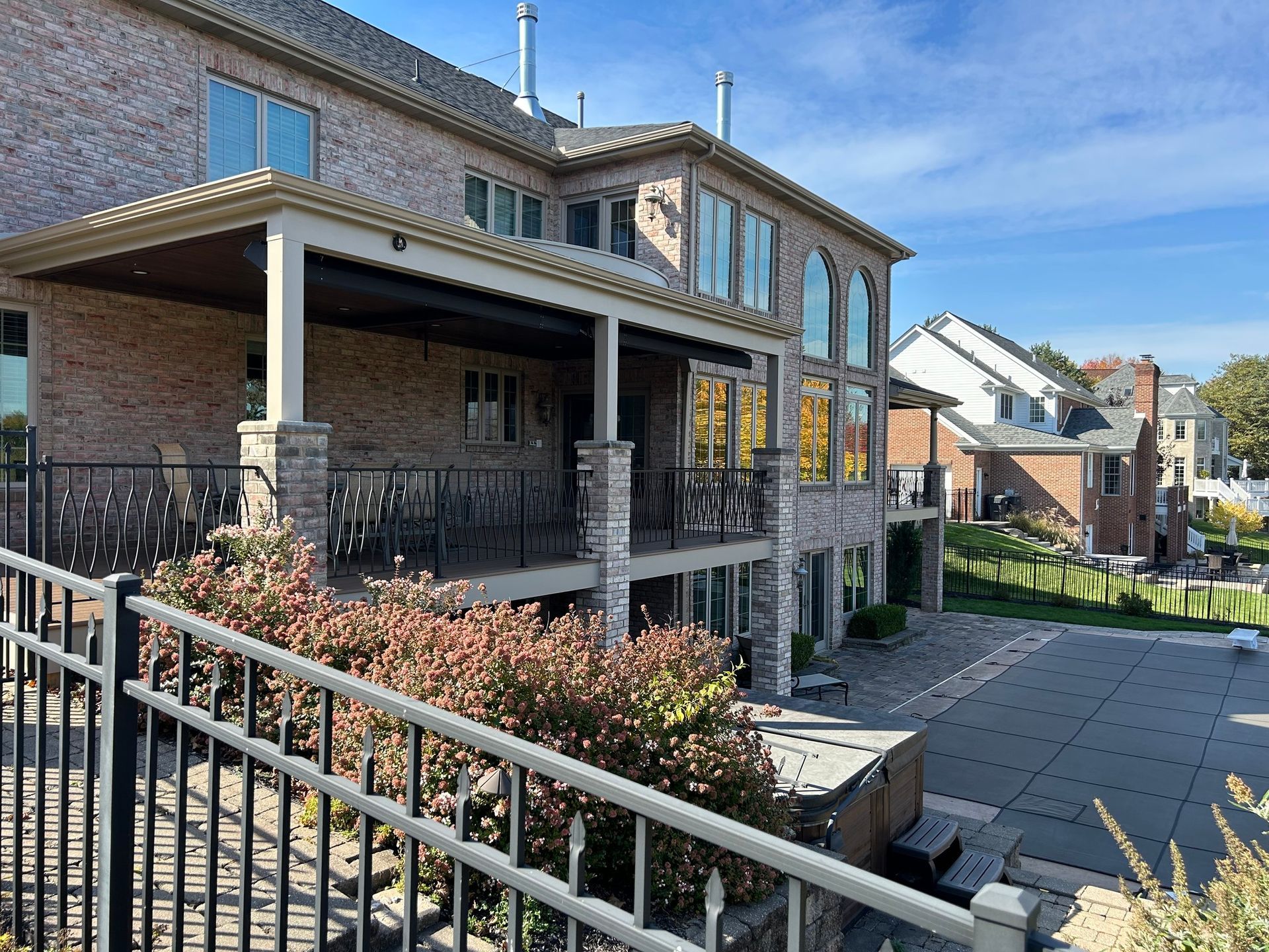 Brick residential walkway with black railings, covered porch, and blue sky
