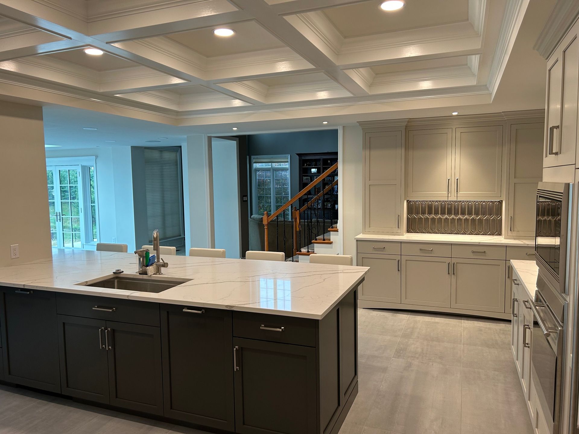 Bright modern kitchen with large island, white cabinets, and recessed ceiling lights