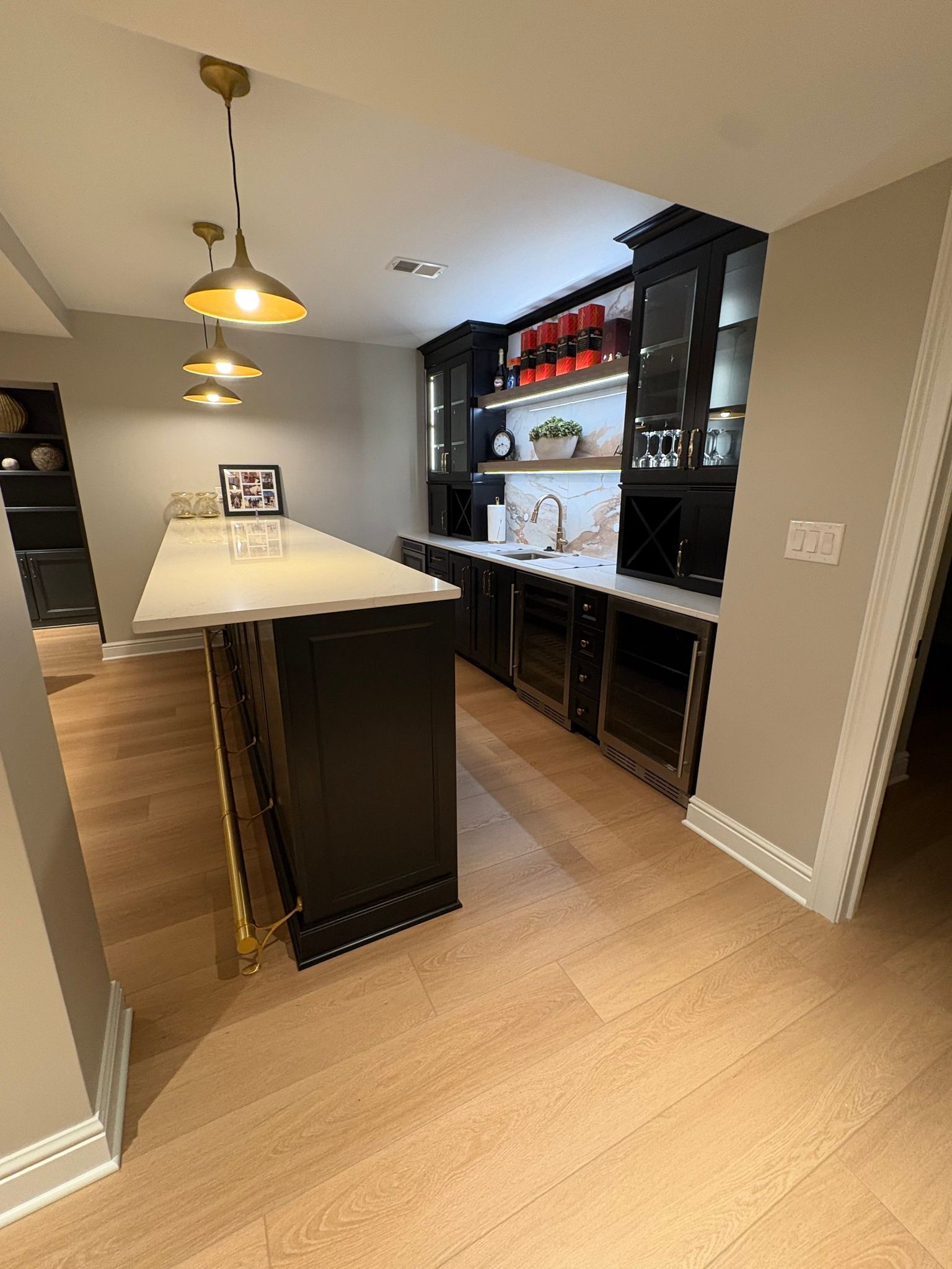 Modern kitchen with a large island, pendant lights, and dark cabinetry with open shelves.