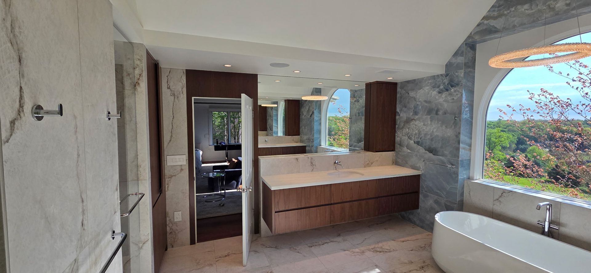 Partially renovated room with built-in cabinets, concrete walls, and a large window overlooking greenery