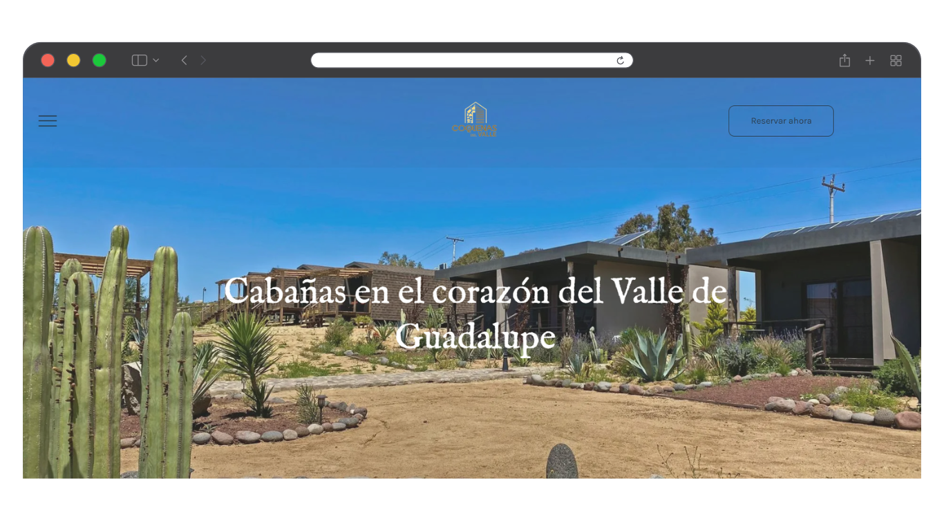 Paisaje del Valle de Guadalupe con cactus y edificios rústicos bajo un cielo azul brillante.
