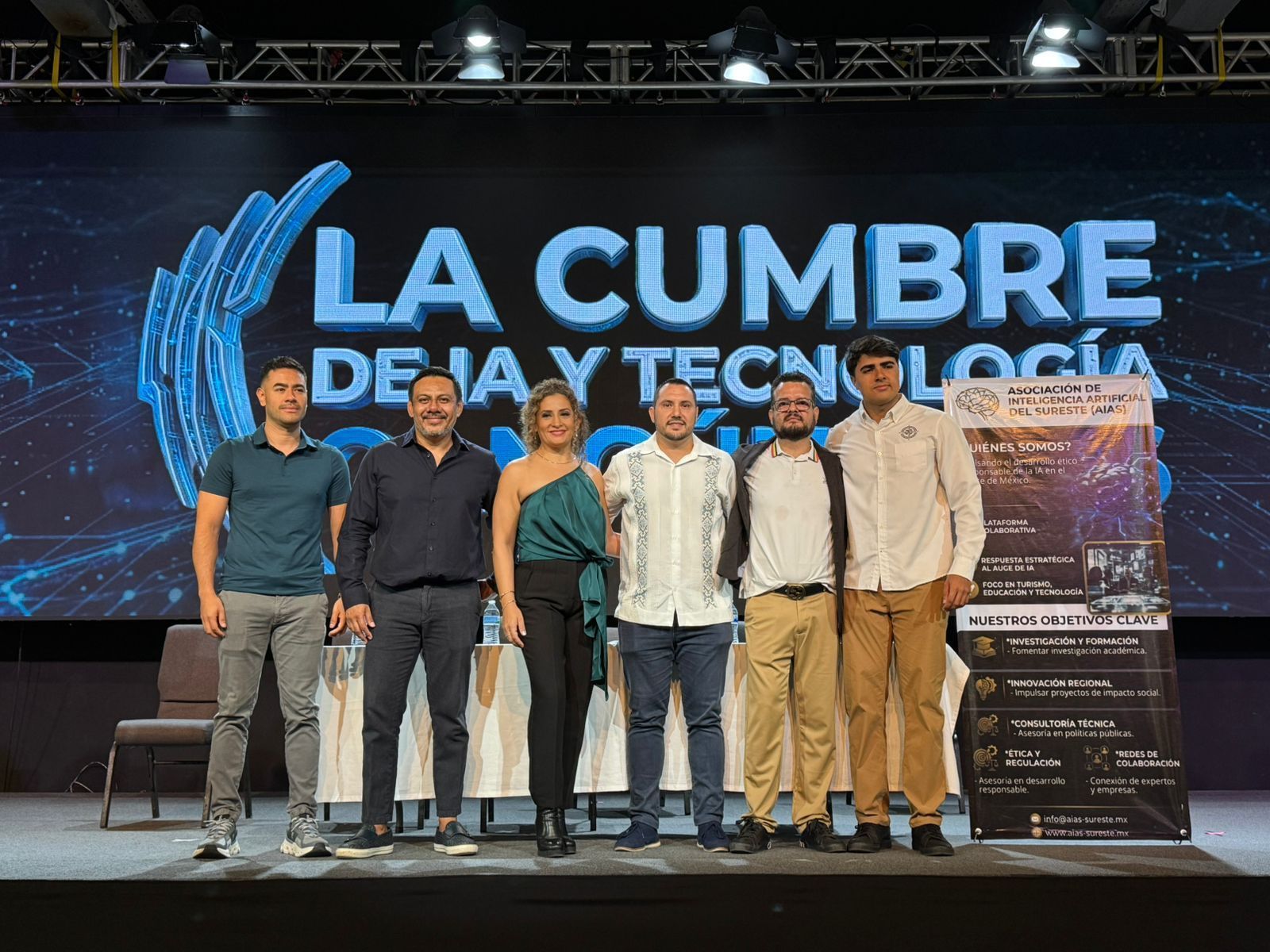 Group of six people onstage at La Cumbre de IA y Tecnología event banner