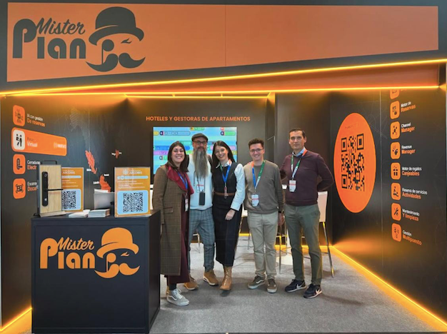 Stand de feria comercial con cuatro personas de pie bajo iluminación naranja y la marca