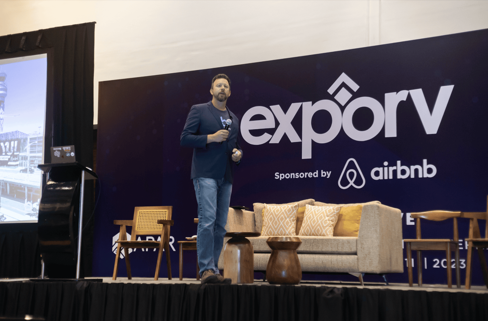 Ponente en el escenario del evento Expory con experiencia en la marca Airbnb y mobiliario moderno para salones.