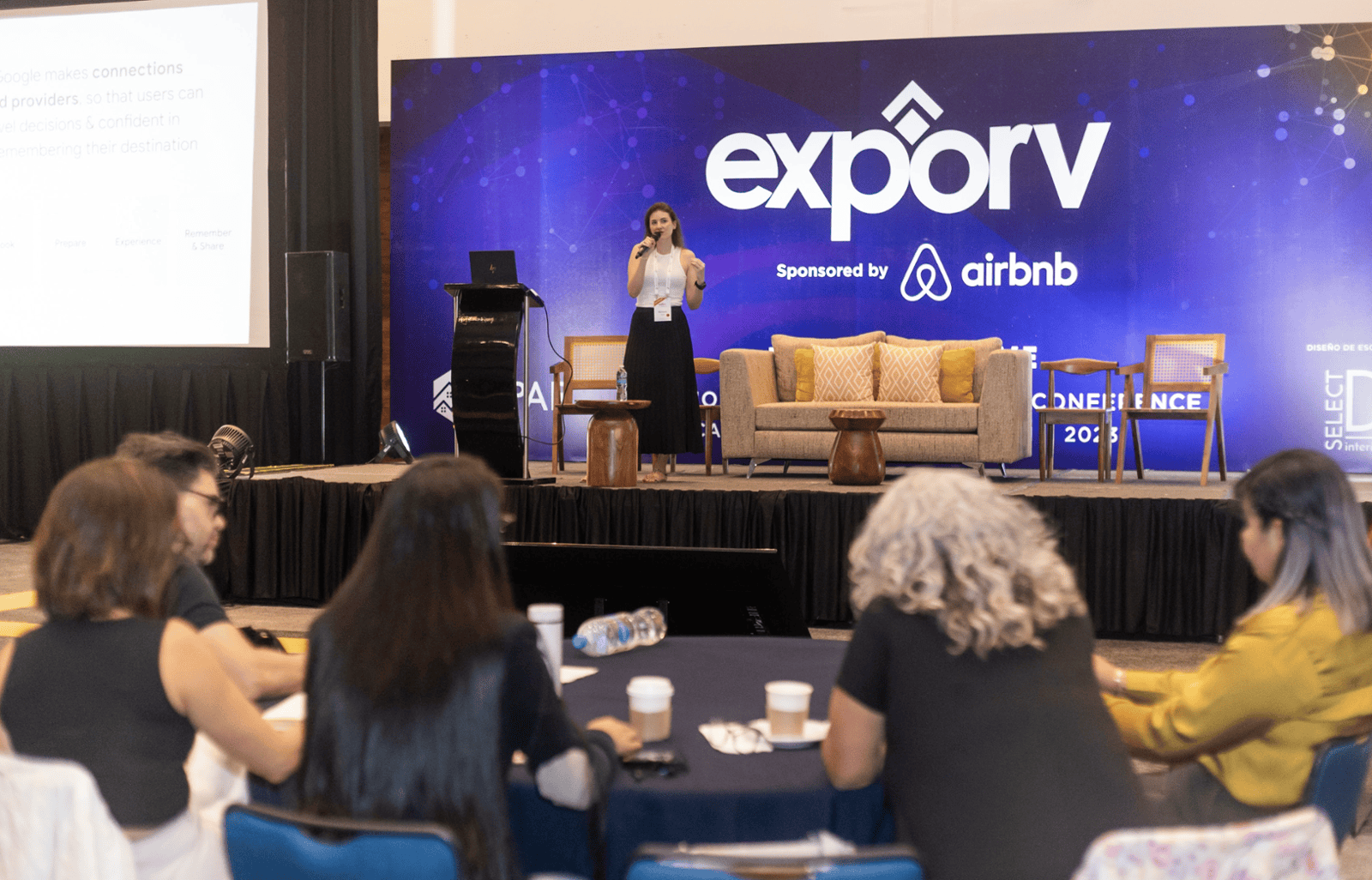 Panel de la conferencia en un escenario con los logotipos de “exporv” y Airbnb, visibles desde el público.