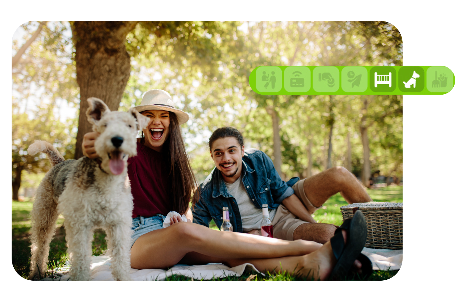 Dos personas y un perro sentados en el césped en un parque soleado, sonriendo bajo los árboles.