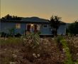 Una casa móvil azul está situada en medio de un campo con montañas al fondo.