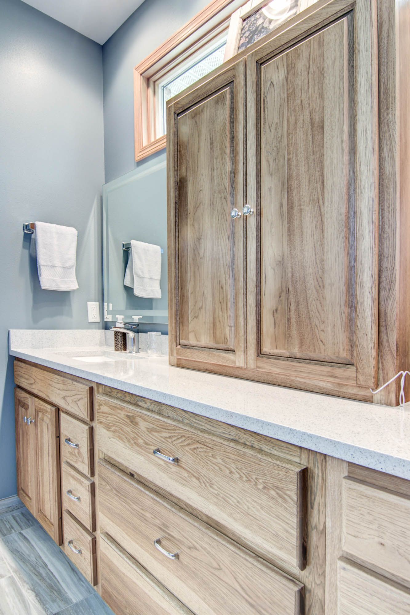 A bathroom with a sink , cabinets , drawers and a mirror.