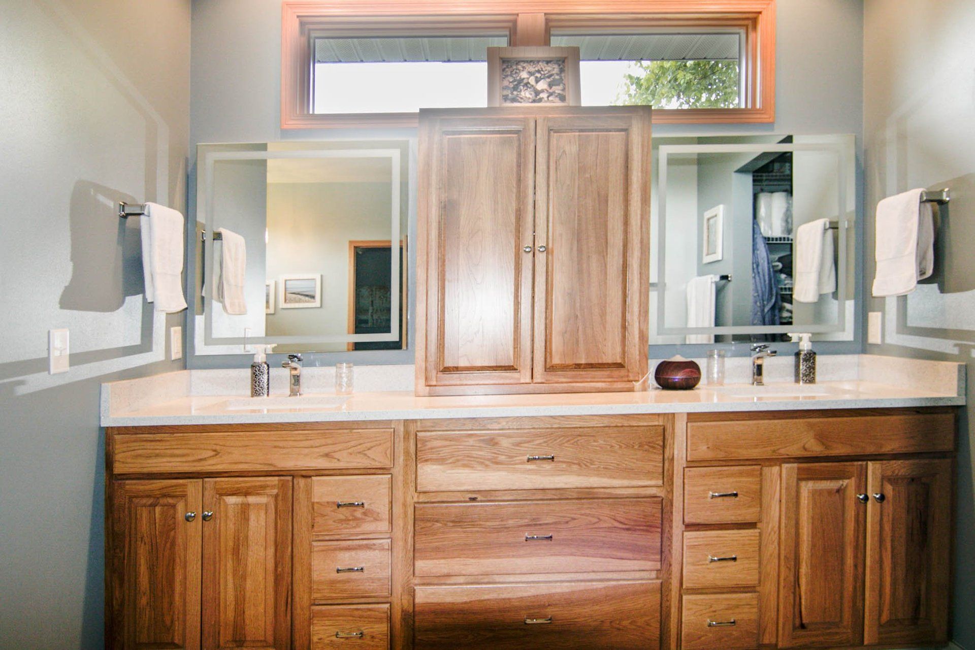 A bathroom with two sinks , two mirrors , and wooden cabinets.