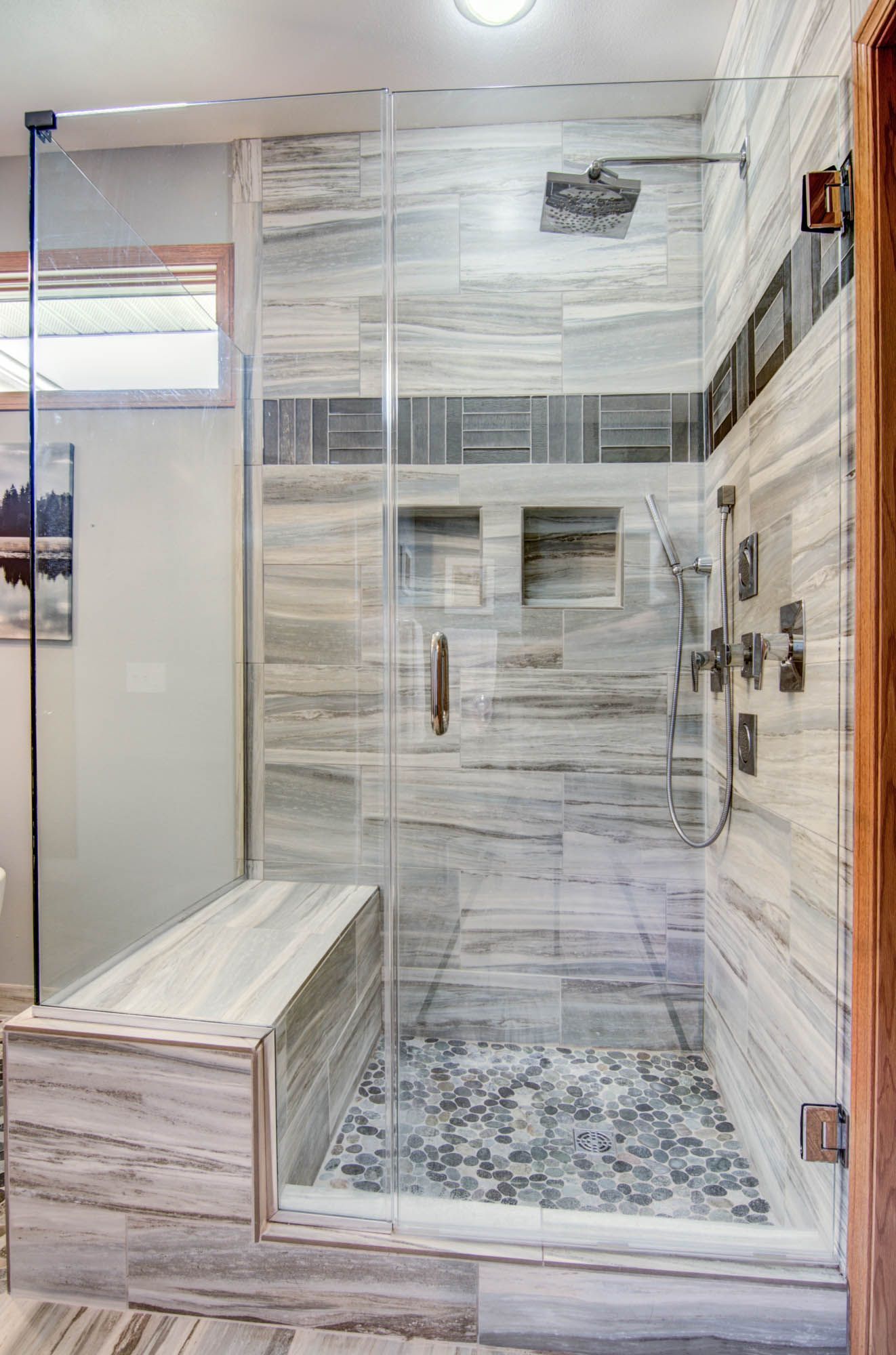 A bathroom with a walk in shower with a bench.
