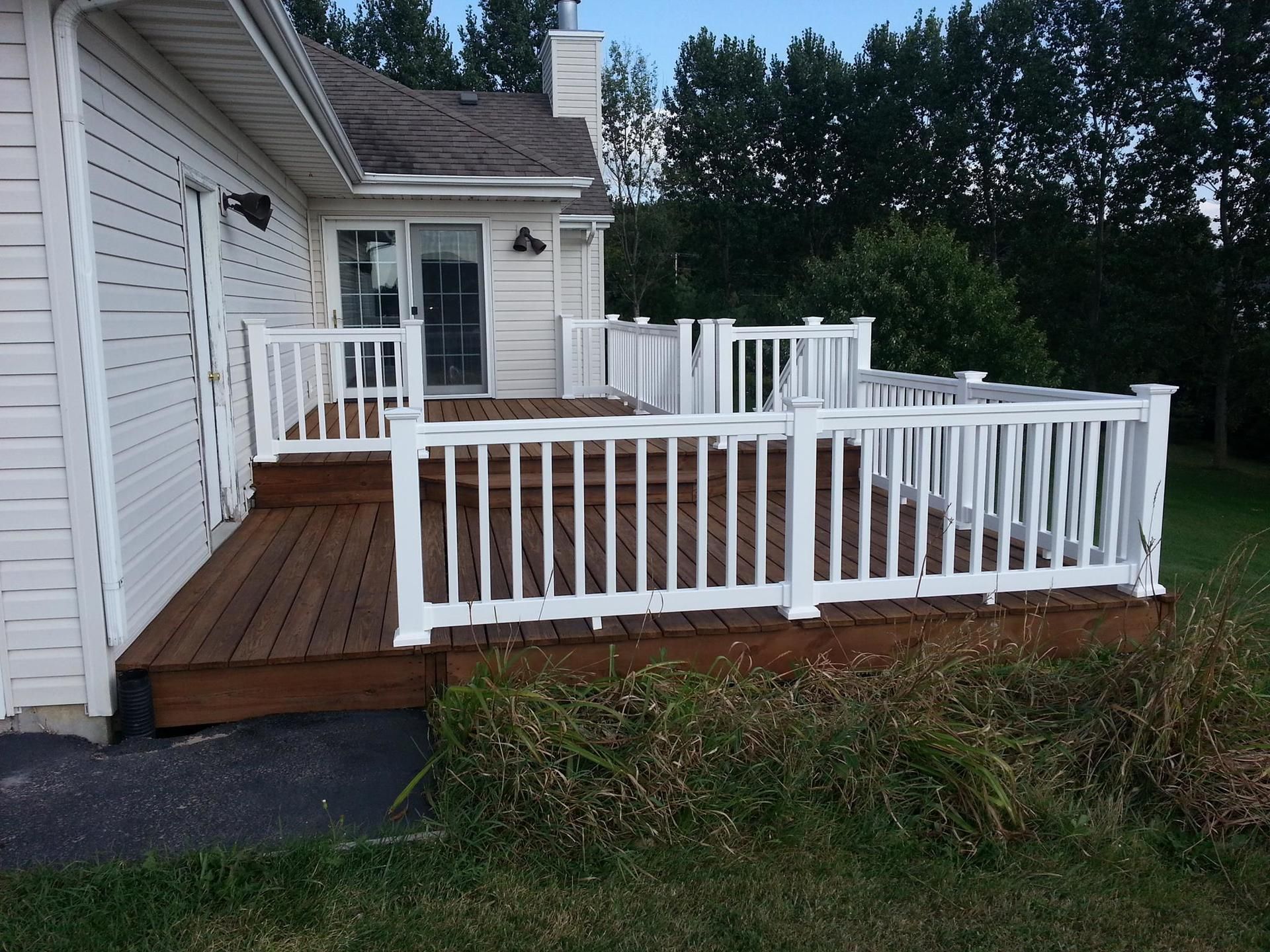 A white house with a wooden deck and white railing