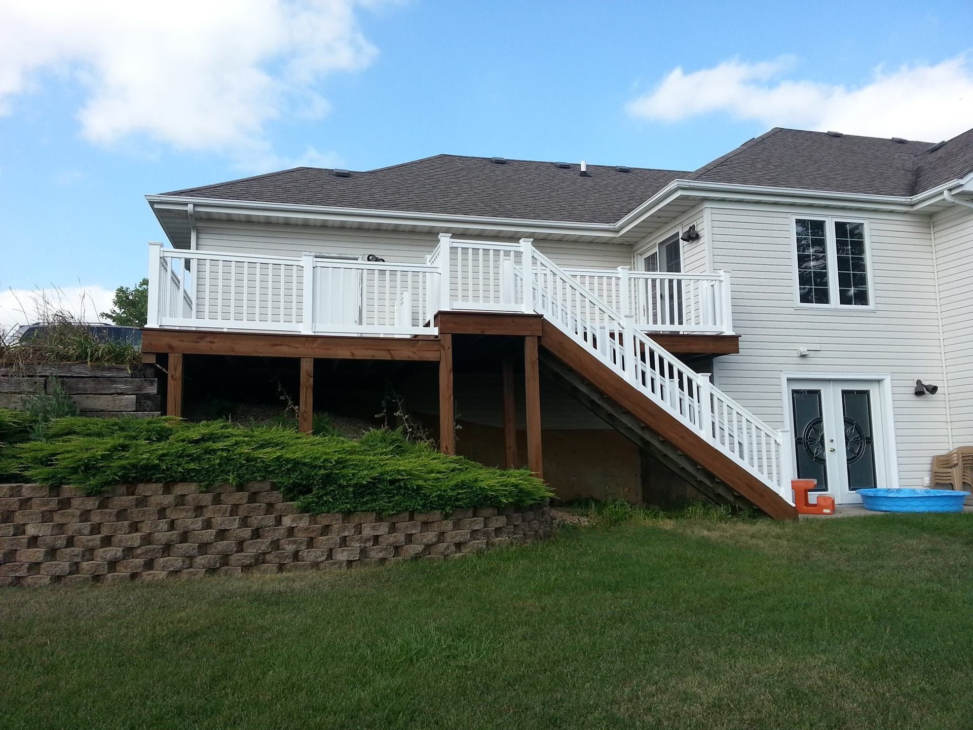 A white house with a large deck and stairs
