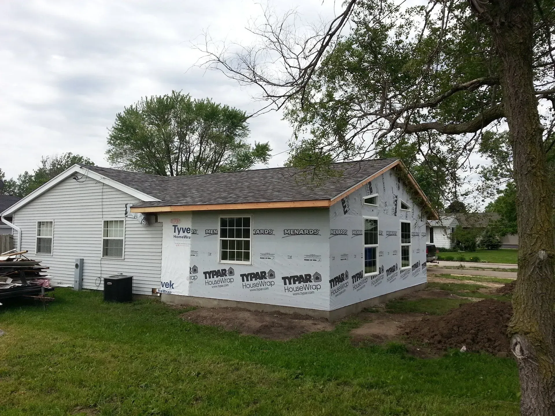 A white house with a gray roof is being remodeled
