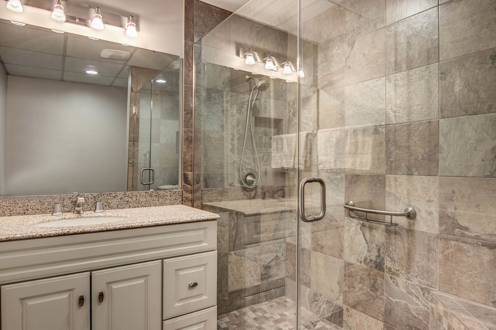 A bathroom with a walk in shower , sink and mirror.