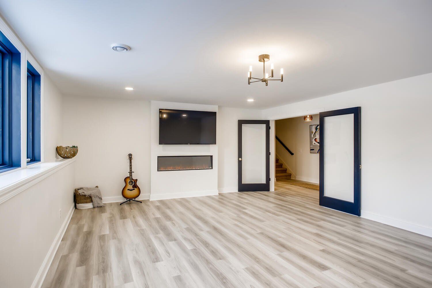 A living room with a guitar and a television on the wall.