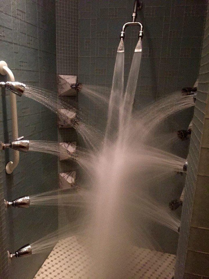 A shower with a lot of shower heads spraying water.
