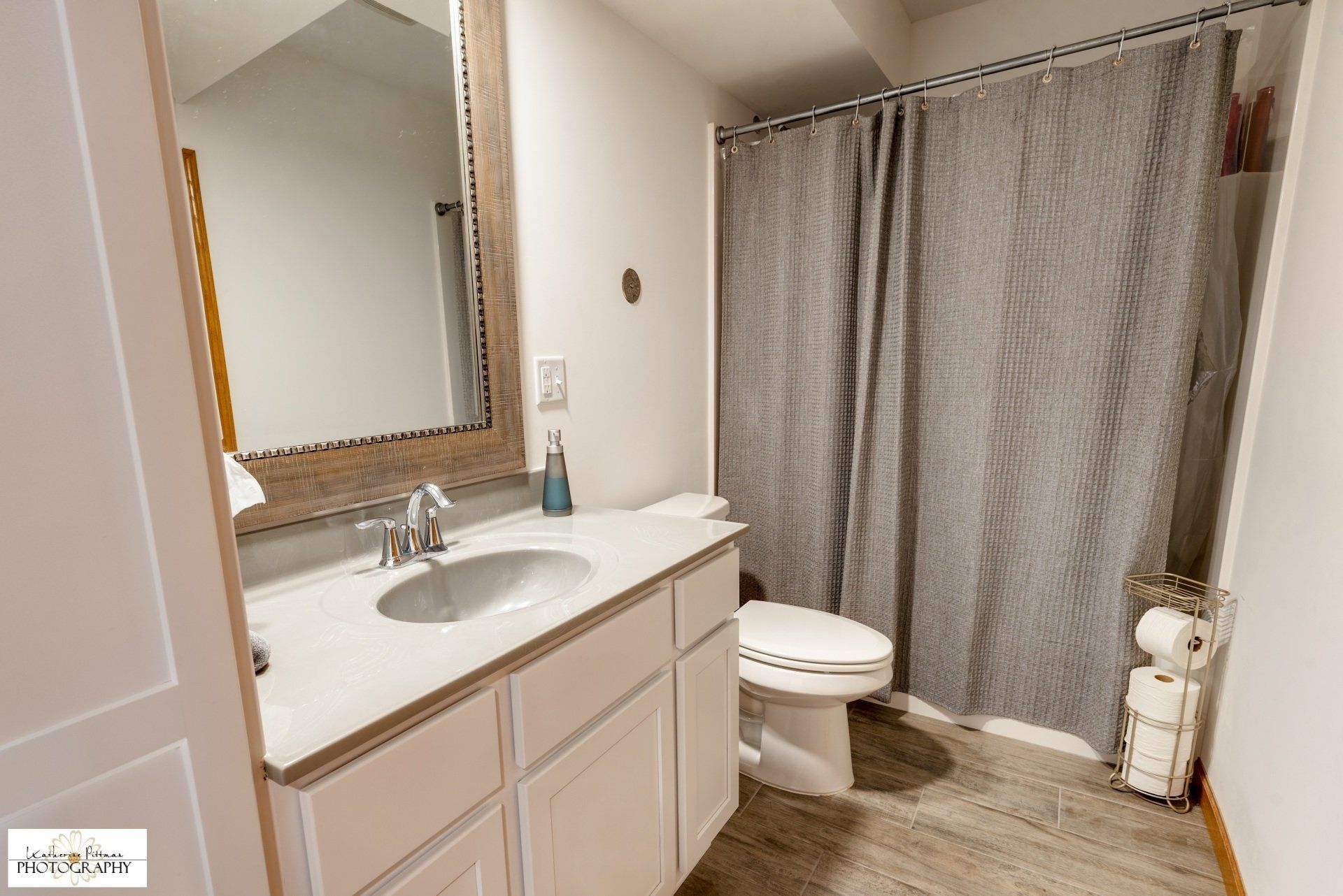 A bathroom with a sink , toilet , shower and mirror.