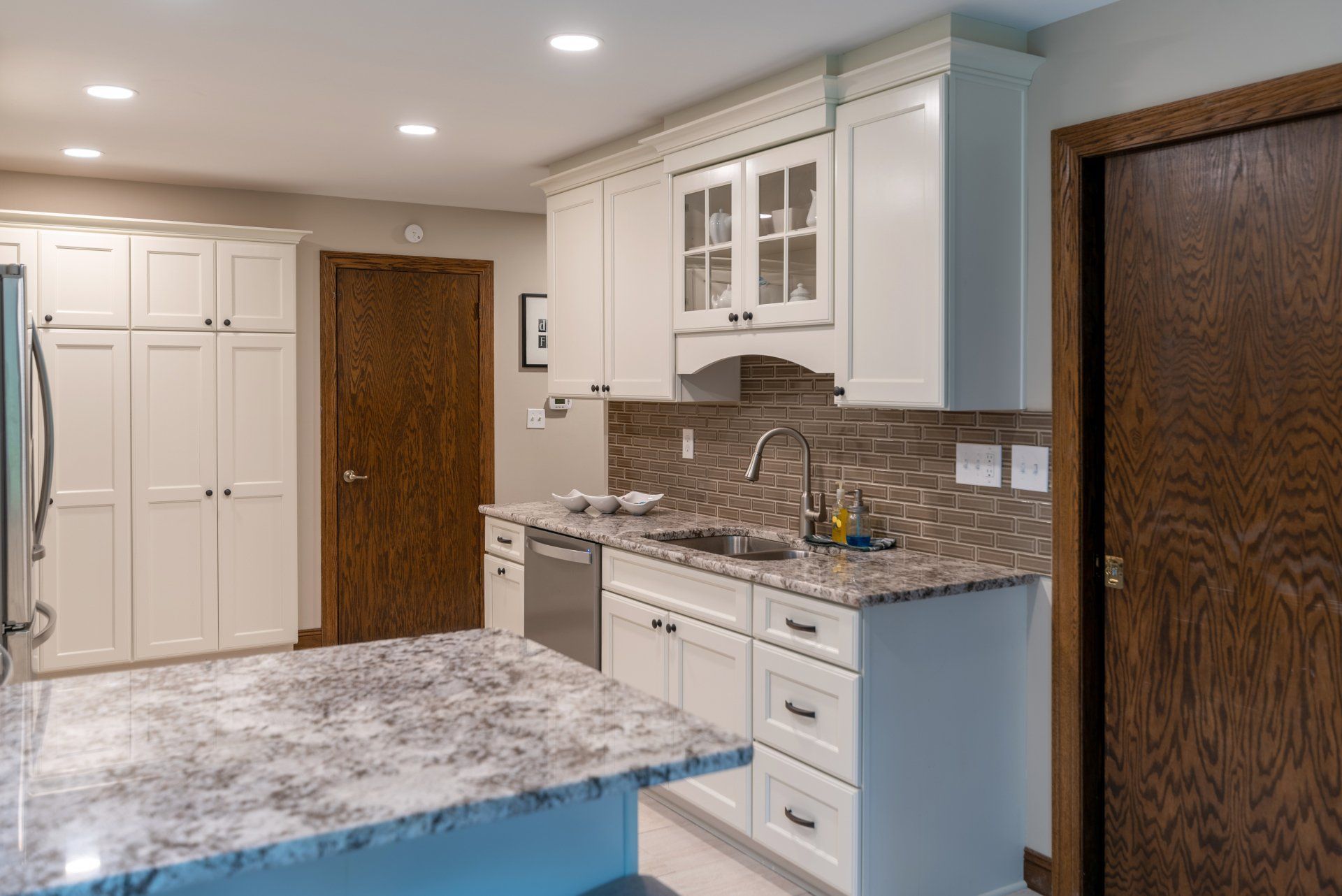 A kitchen with white cabinets , granite counter tops , and stainless steel appliances.