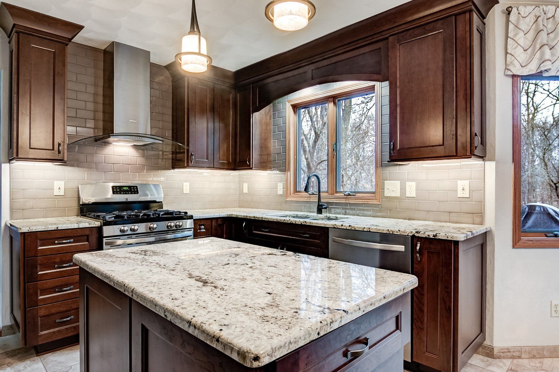A kitchen with granite counter tops , stainless steel appliances , and wooden cabinets.