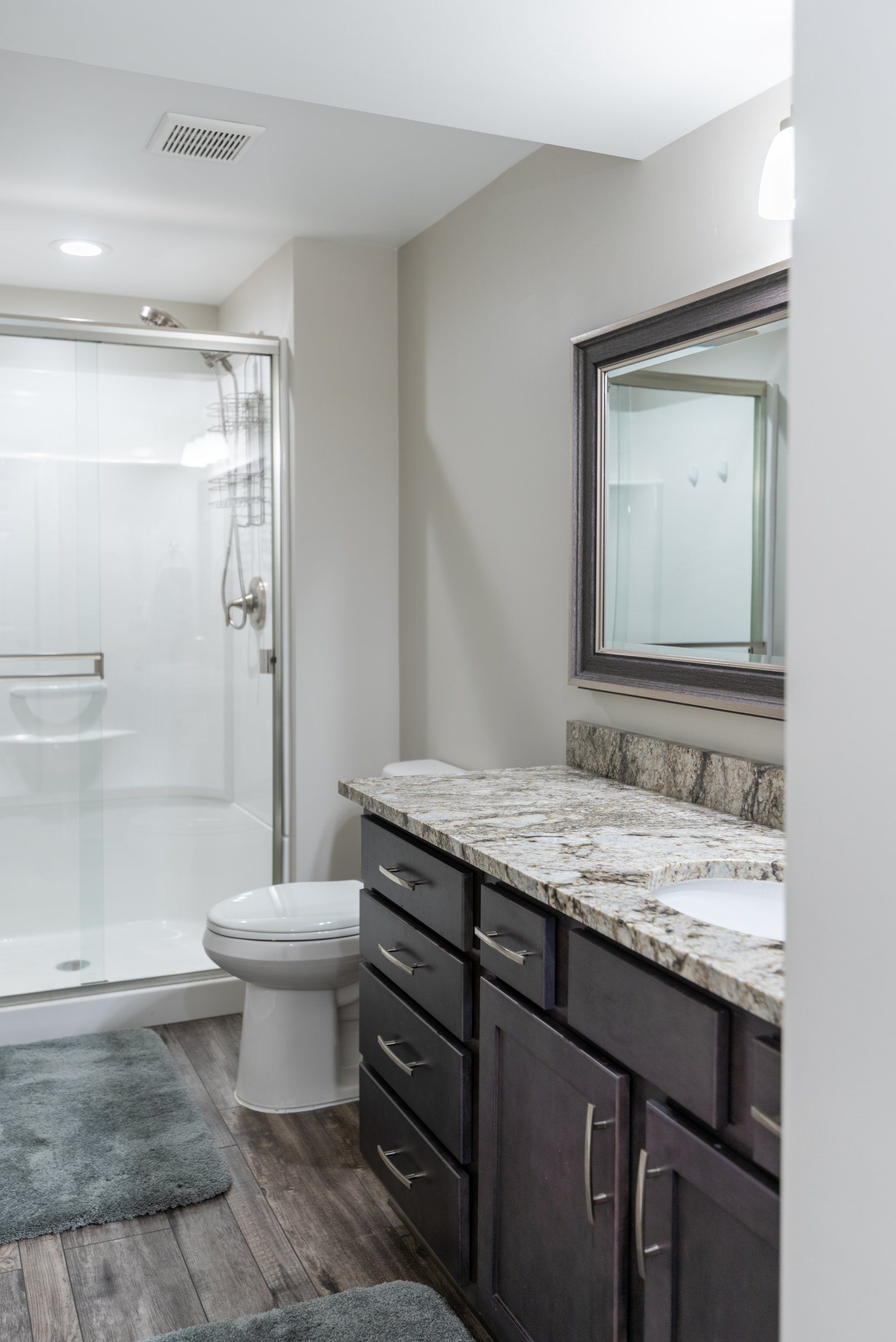 A bathroom with a toilet , sink , mirror and shower.