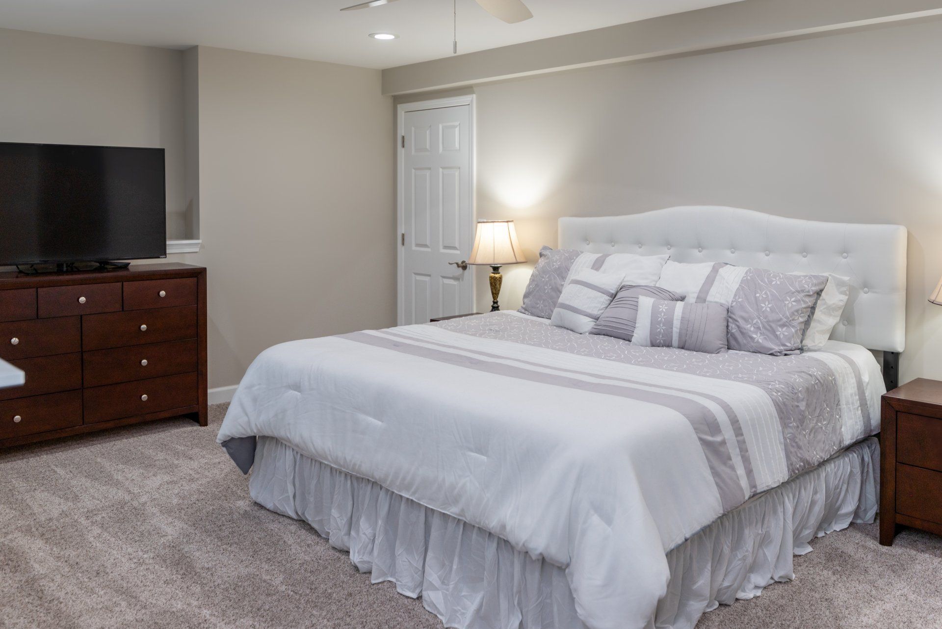 A bedroom with a king size bed , dresser , television and nightstand.