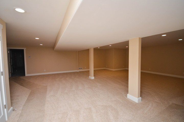 An empty basement with tan walls and tan carpet
