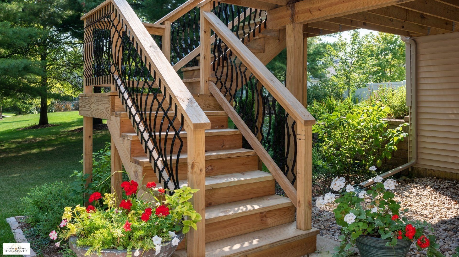 A wooden deck with stairs and flowers in front of it
