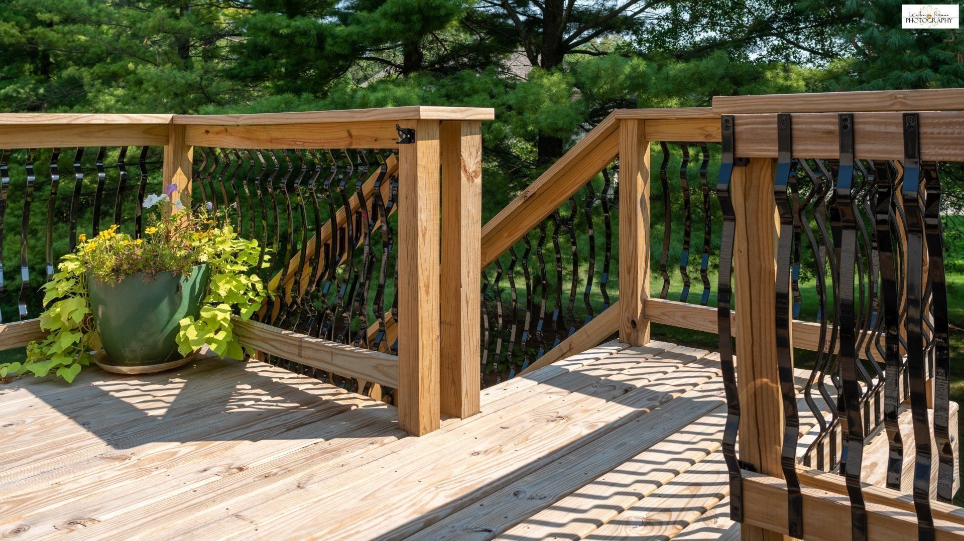 A wooden deck with a metal railing and a potted plant on it.