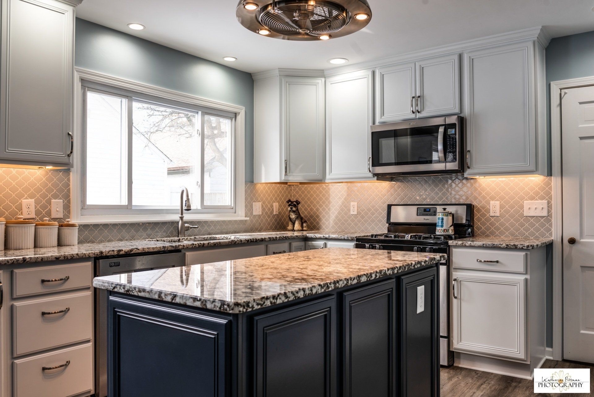 A kitchen with white cabinets , granite counter tops , stainless steel appliances , and a large island.