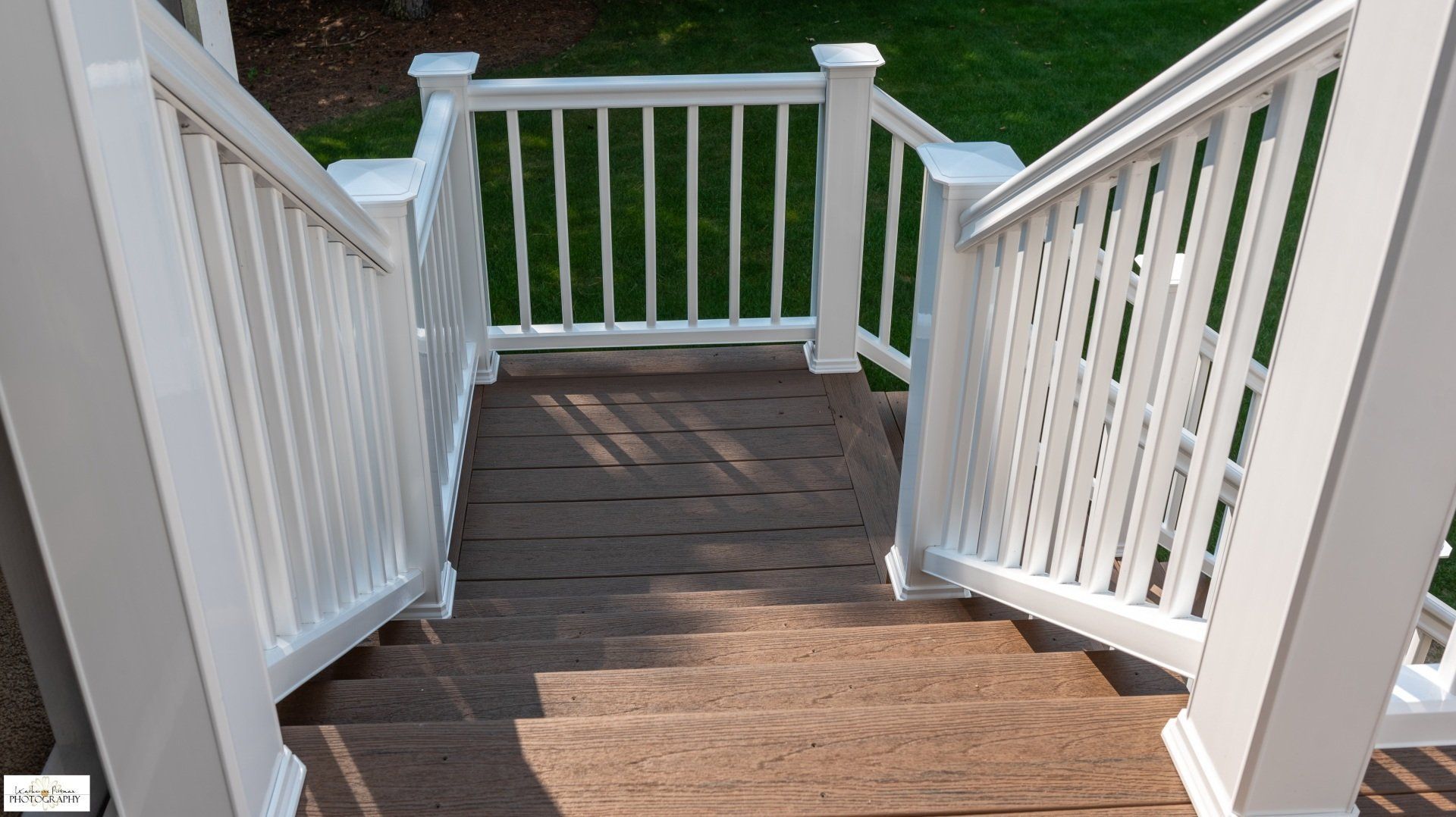 A set of stairs leading up to a deck with a white railing.