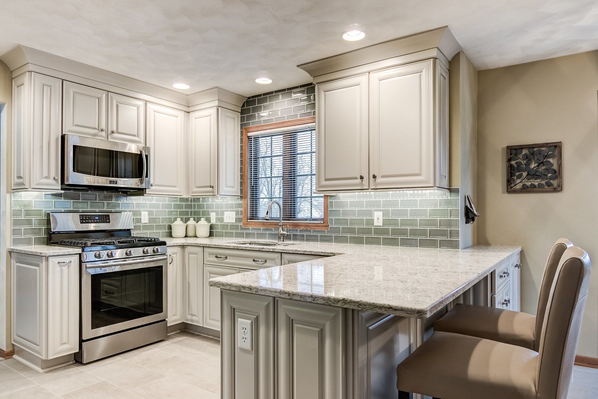 A kitchen with white cabinets , granite counter tops , stainless steel appliances and a large island.