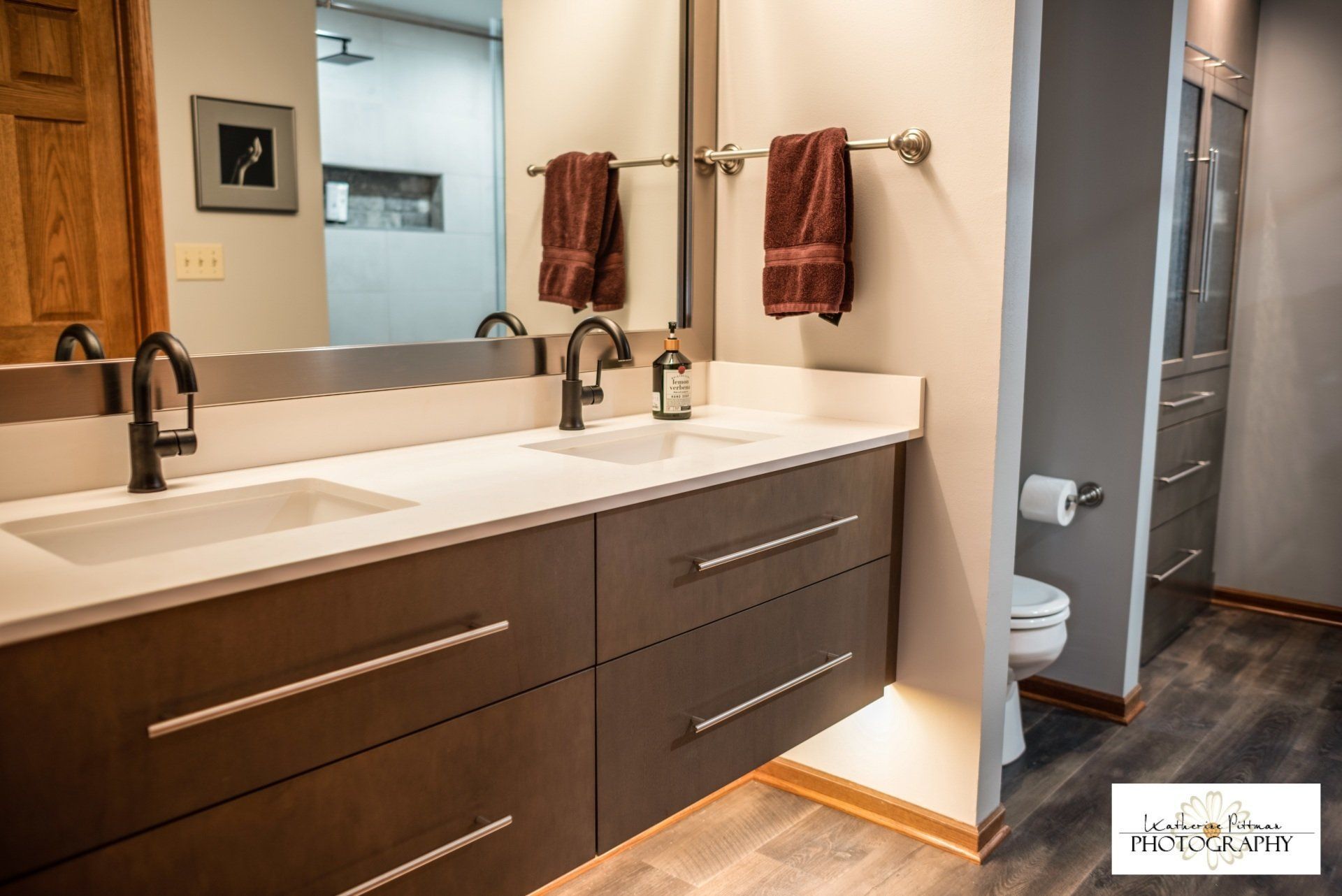 A bathroom with two sinks , a toilet and a mirror.