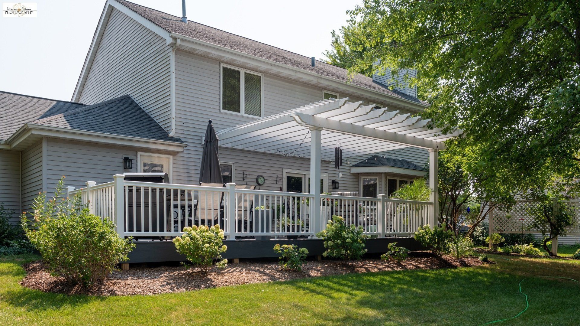 A large white house with a large deck and pergola.